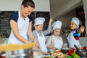 Photo of a group of children having fun while food fighting, during cooking class with a chef